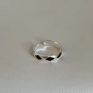 Detailed close-up of a silver adjustable ring with dark red enamel diamond patterns