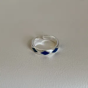 Detailed close-up of a silver-tone open ring featuring blue enamel diamond patterns