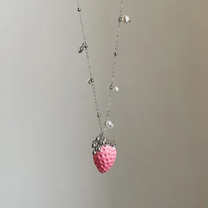 Detalle del colgante de fresa rosa con textura y cadena de plata con perlas