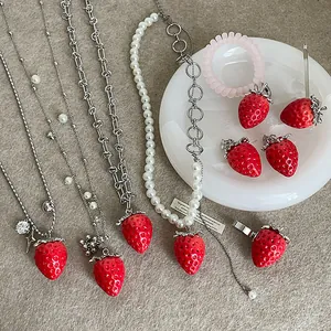 Rote realistische Erdbeerschmuck-Set mit Halsketten und Ohrringen auf einem Tablett