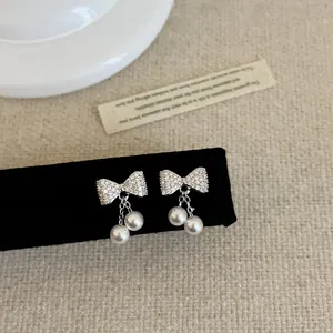Detail van zilveren strikoorbellen met zirkonia pavé en hangende witte parels