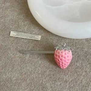 Detalle de pinza para el pelo de fresa rosa con acabado de resina texturizada y hoja de plata