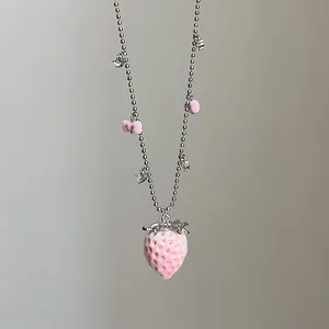Nahaufnahme des rosa beflockten Erdbeeranhängers mit silberner Kugelkette und Strass