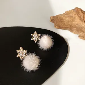 Detailed view of elegant snowflake earrings featuring white fur pom poms and crystals