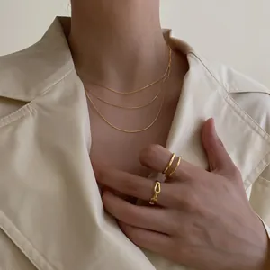 Ensemble de colliers dorés multicouches minimalistes pour femme avec manteau beige chic