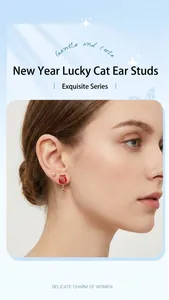 Detailed close-up of lucky red fortune bag stud earrings with gold character and bow details