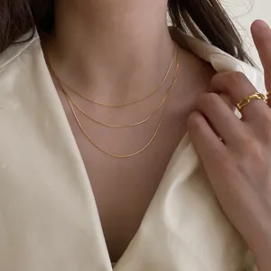 Gros plan d'un élégant collier à trois rangs en or porté par un mannequin en chemise