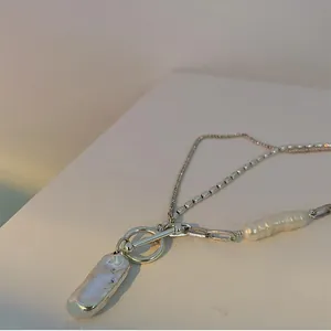 Dettaglio collana a doppia catena argento con perla barocca e ciondolo in metallo fuso