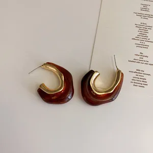 Detail view of retro geometric C-shape earrings with amber resin and gold metal finish