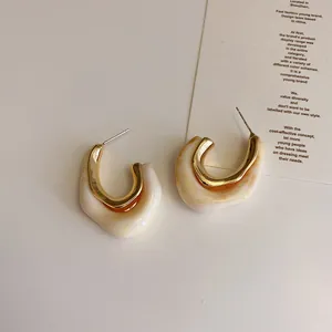 Close-up of C-shaped gold metal and cream marble resin earrings with S925 silver pins