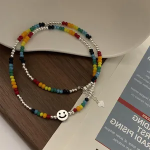 Gros plan du collier de perles colorées avec pendentif smiley argenté et petit cœur