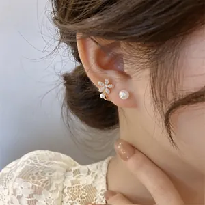Close-up of elegant flower stud earrings with zircon and pearl on model's ear