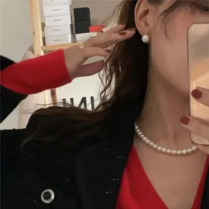 Collana di perle bianche classiche e orecchini a lobo abbinati indossati nello stile quotidiano