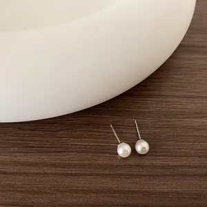 Primo piano di orecchini a perno con perle bianche su legno vintage e sfondo bianco