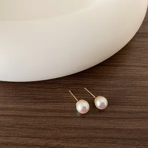 Primo piano dettagliato di orecchini di perle da 8mm con perni dorati su legno e ceramica