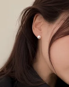 Dettaglio di orecchini a perno con perla da 8mm minimalisti indossati da una modella