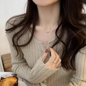 Gros plan du collier minimaliste avec pendentif cylindrique en or et zircon porté