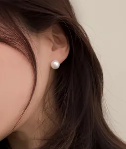 Primo piano di un orecchino con perla bianca tonda indossato per un look elegante