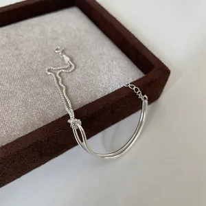 Minimalist silver-tone double-layer metal bracelet featuring a polished tube and knot design