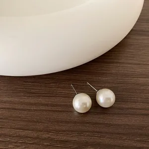 Primo piano di orecchini a perno con perle minimalisti e lucentezza su base in legno