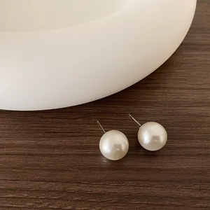 Dettaglio del marchio S925 su orecchini di perle minimalisti su sfondo di legno scuro