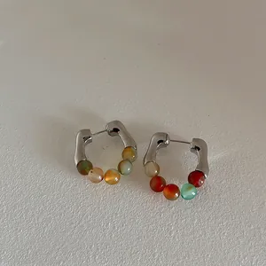 Detail of C-shaped silver textured earrings with multi-color natural stone beads