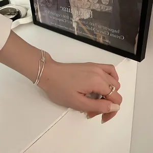 Detailed view of minimalist knot silver bangle and gold pearl ring set on a white table