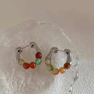 Close-up of hoop earrings with natural gemstones and pearls on a glass tray