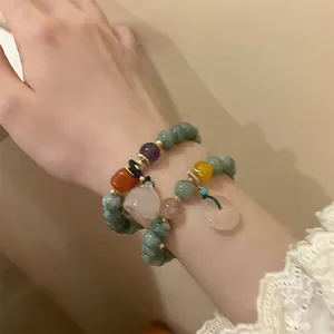 Detail of beaded bracelets with jade stones, white rabbit charm and lace sleeve detail