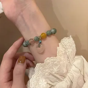 Detail of French vintage natural stone beaded bracelet with pink heart charm on wrist
