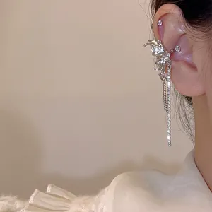 Κοντινό πλάνο από ασημένιο ear cuff πεταλούδα με μακριές φούντες και λαμπερά στρας