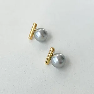 Minimalistische Goldstab-Ohrstecker mit grauen Perlen auf weißem strukturiertem Grund