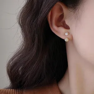 Detail of freshwater pearl and zircon gold stud earrings shown on a female model