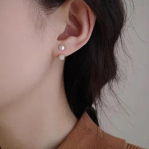 Macro detail of model wearing gold zircon ball and freshwater pearl earrings on earlobe