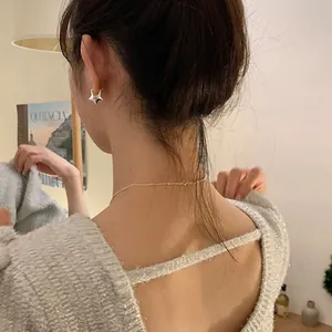 Primer plano de un pendiente de estrella 3D plateado y un collar de cuentas
