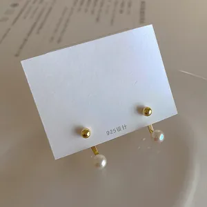 Detailed view of 925 silver needle pearl earrings with gold spheres on display card