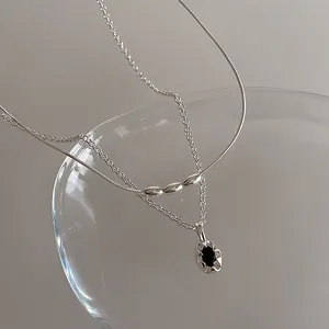 Détail d'un collier argenté à deux couches avec perles de serpent et pendentif noir