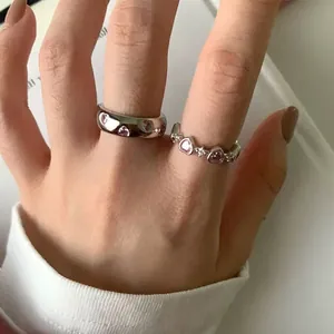 Minimalist silver open ring set featuring pink zircon heart gems on a lady's hand