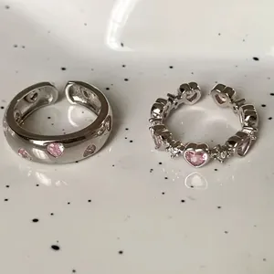 Macro shot of S925 silver rings with pink heart zircon and hollowed design on a plate