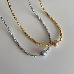 Elegante unregelmäßige Metallperlenkette in Gold und Silber auf hellgrauem Hintergrund