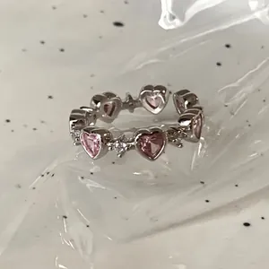 Close-up of pink heart-shaped zircon stones set in a vintage silver-finish open ring