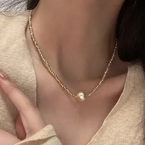 Elegante goldene Kordelkette mit großem Metallperlen-Anhänger an einem Model getragen
