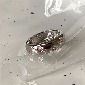 Macro shot of polished silver wave ring with pink heart-shaped zircon stones