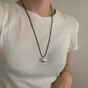 Minimalist long cord necklace with metallic 3D heart pendant on a white t-shirt model