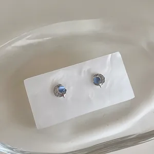 Detail of star and moon stud earrings featuring a blue opal stone and micro-set crystals