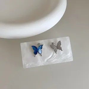 Detail of asymmetrical butterfly earrings featuring blue enamel and sparkling zircon inlay