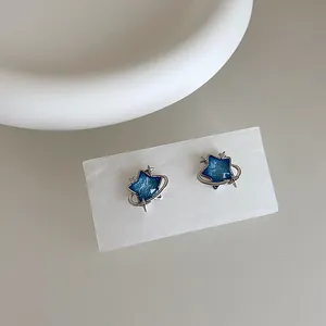 Detail view of blue star earrings with silver planetary orbit and sparkling crystals