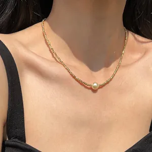 Nahaufnahme einer eleganten Goldperlenkette mit zentraler Goldperle an einem Modell