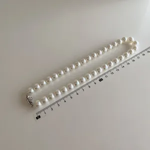Vue détaillée du collier de perles blanches de 10 mm avec fermoir argenté et règle de mesure