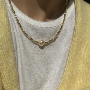 Nahaufnahme eines minimalistischen Perlenanhängers an einer feinen goldener Kugelkette